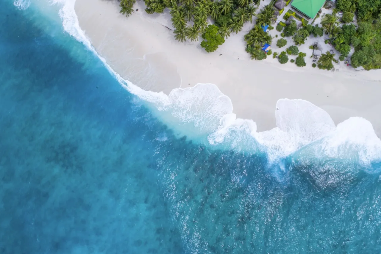 Onda turquesa a quebrar sobre areia clara