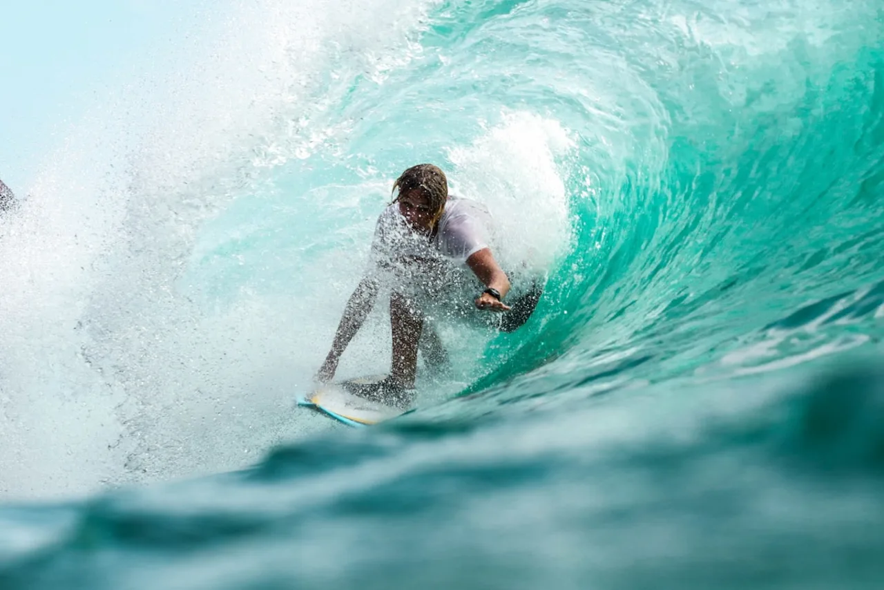 Surfista a deslizar numa onda turquesa